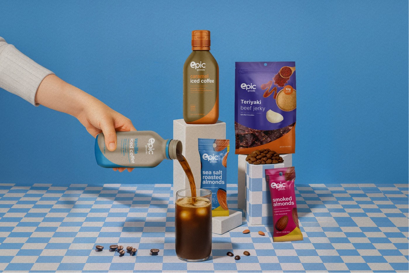 Epic Goods snack and beverage lineup: gummy pouch, popcorn, snack-nut pack, jerky, iced coffee, smoothie, and electrolyte water in bold color-blocked packaging