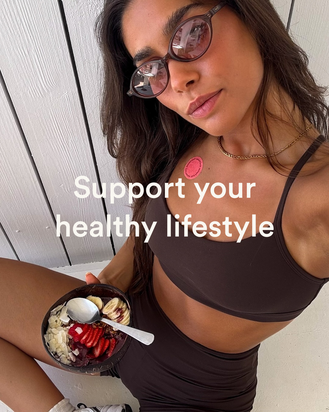 Lifestyle image of a woman in activewear holding an acai bowl with a Kind Patches patch on her chest and the words 'Support your healthy lifestyle'